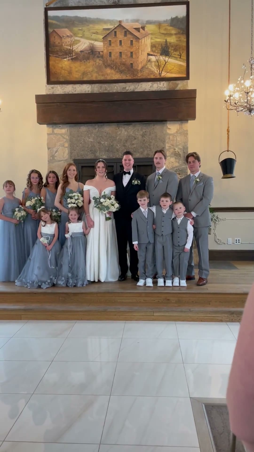 Sara's wedding party of fourteen gathered in front of the fireplace at Ancaster Mill