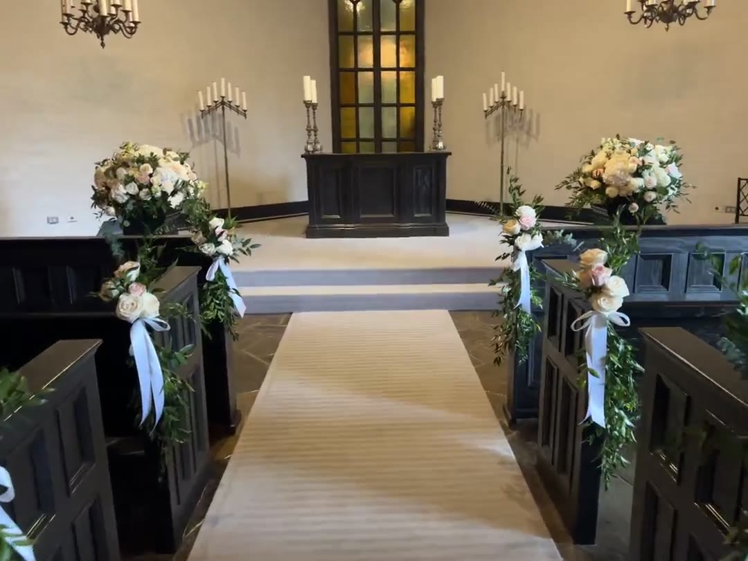 Miriam and Quinn's chapel aisle at Old Mill Toronto, with dark wooden pews dressed in greenery and roses, and candelabras at the altar
