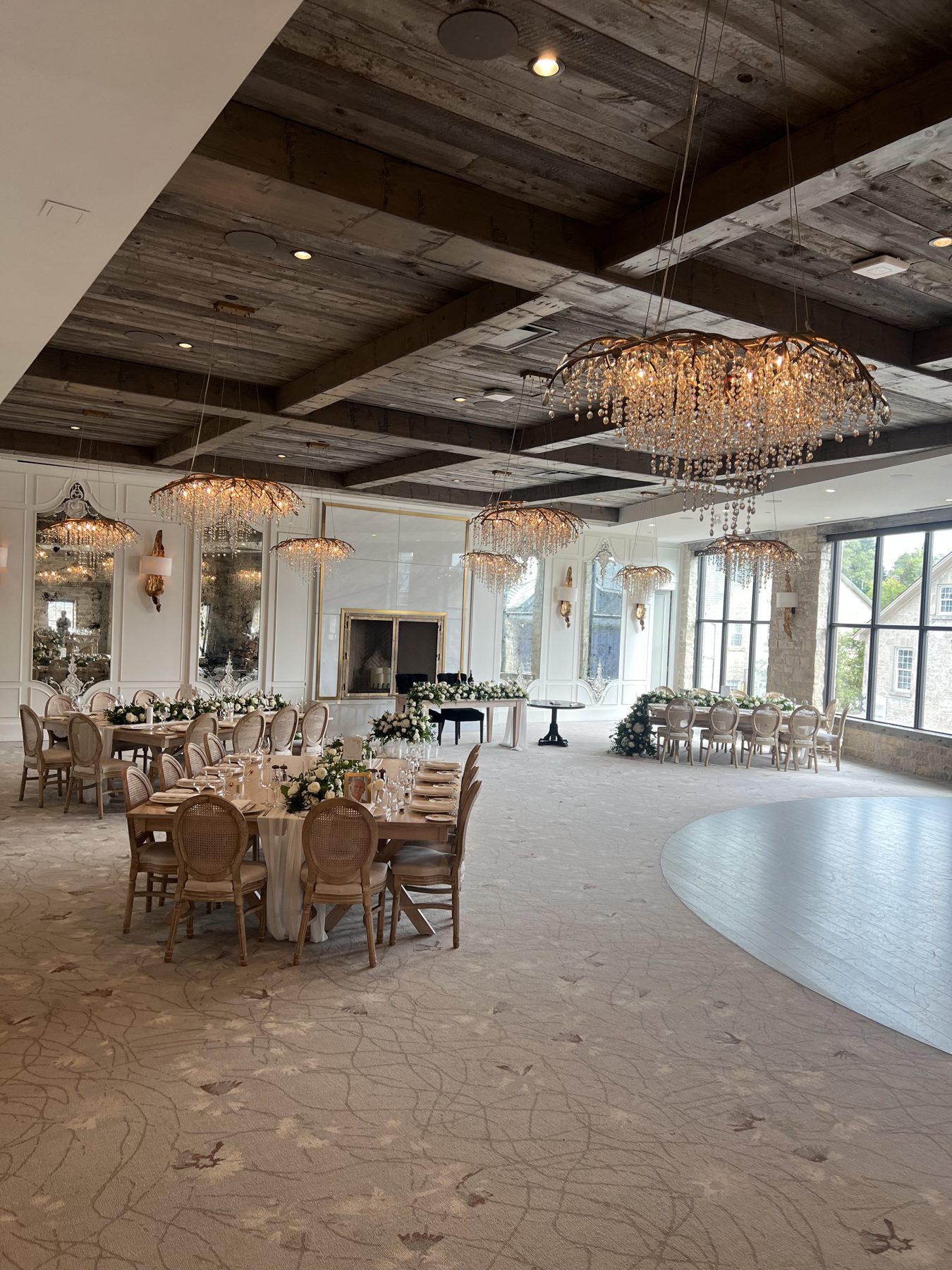 Elora Mill ballroom with branch chandeliers, a wood-beamed ceiling and tables dressed with white florals and greenery