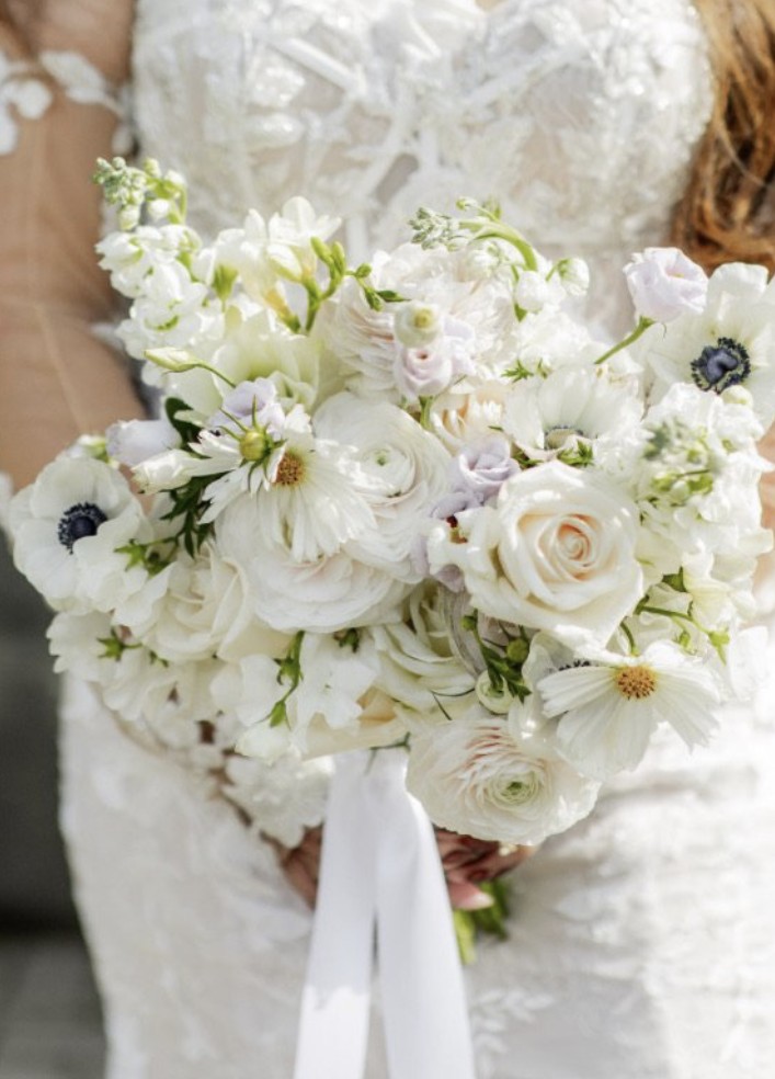 Shea's bridal bouquet at Casa Loma, white anemones, cosmos, ranunculus, roses and stock tied with a long white ribbon, against her lace gown