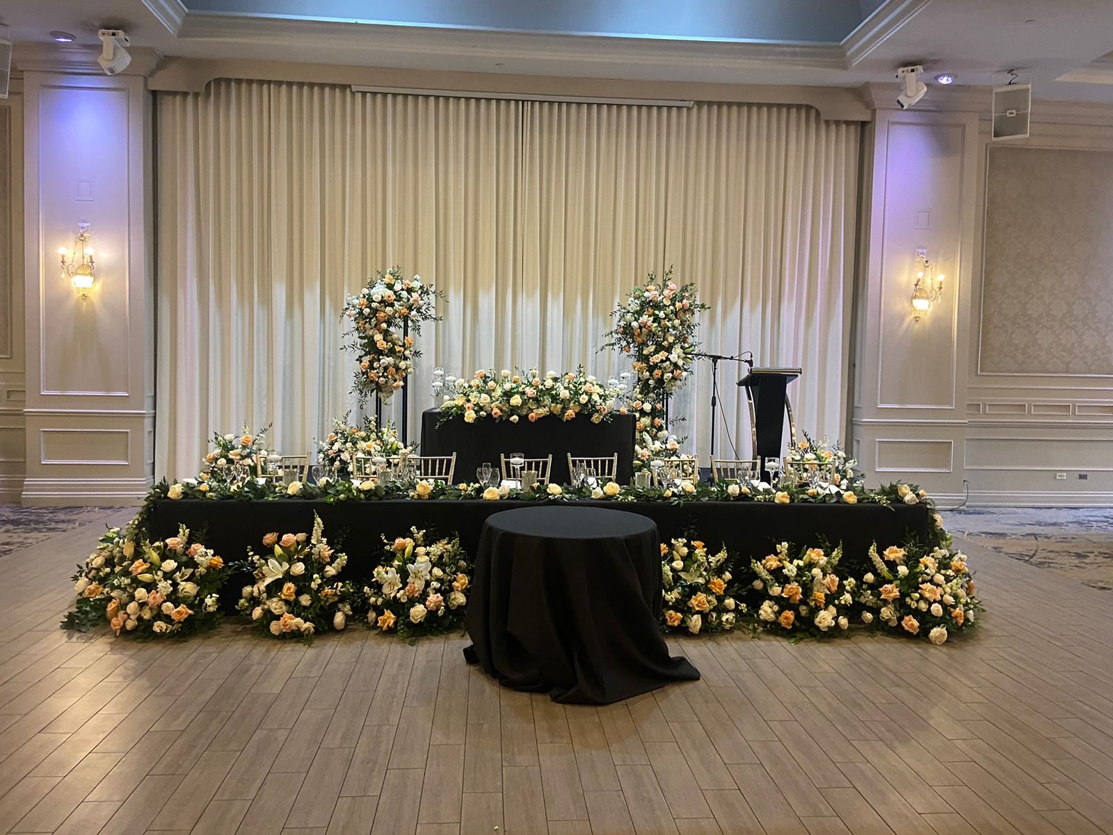 Raised sweetheart table in black linen with peach and cream roses, floral columns and floor arrangements