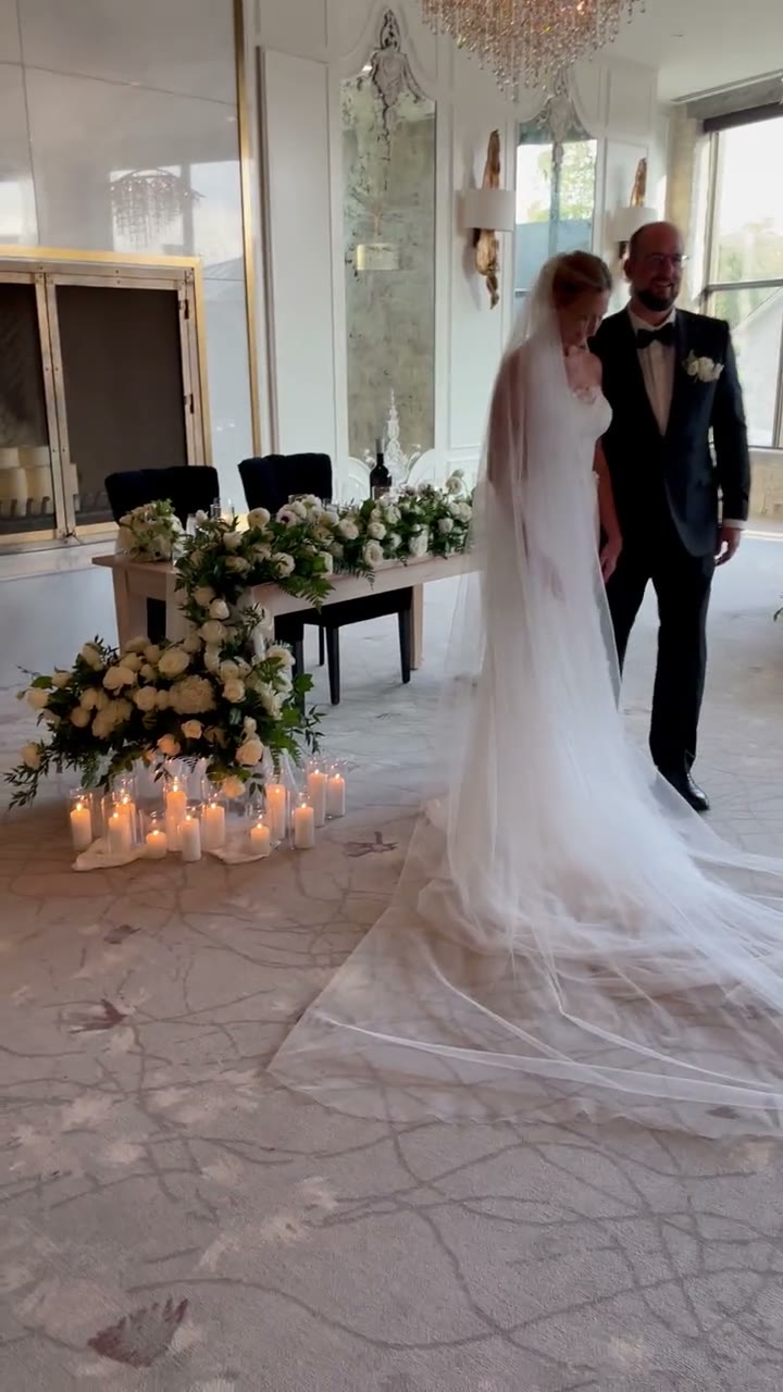 Susan and Geoff with a long veil beside white florals and candles at Elora Mill